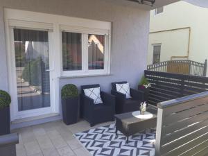 a patio with chairs and a table and windows at Apartman Gold in Požega