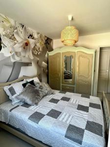 1 dormitorio con 1 cama con una manta a cuadros y flores en A L'orée du Bois, en LʼÉguille