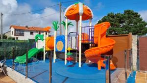 un parque infantil con un equipo de juegos anaranjado en Apartamentos Coral Do Mar III en Montalvo