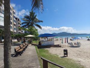 a beach with benches and umbrellas and the ocean at APTO COM VISTA PARA O MAR in Itapema