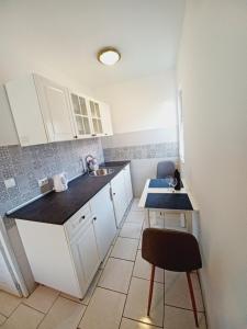 a kitchen with white cabinets and a sink and a stool at Apartments Kati in Orebić