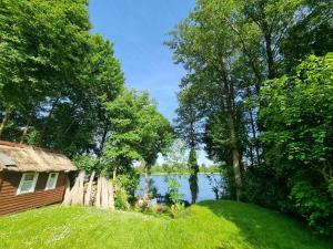 ein Haus im Gras neben einem See in der Unterkunft Haus Seeblick in Stary Gieląd