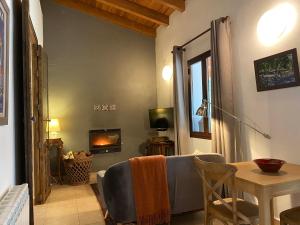 ein Wohnzimmer mit einer Couch und einem Tisch und einem Fernseher in der Unterkunft Valle del Arroyo Casas Rurales - B&B - Solo adultos in Cortelazor