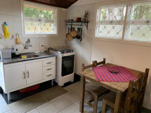 a kitchen with a table and a sink and a stove at Chalé da Araucária in Campos do Jordão