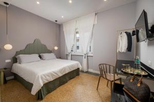 een slaapkamer met een bed en een tafel met een stoel bij NUE SUITES in Sassari