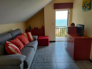 ein Wohnzimmer mit einem Sofa und einem TV in der Unterkunft Apartamento Loft A Estivada in Rosal
