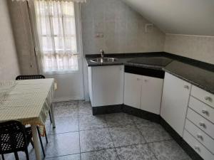 uma cozinha com um lavatório e uma mesa com uma mesa; em Apartamento Loft A Estivada em Rosal