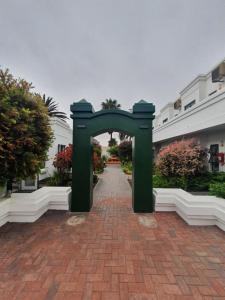 a green archway in the middle of a brick road at Langholm Hotel in Walvis Bay
