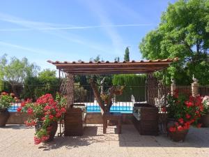 a wooden pergola with flowers and a swimming pool at Alojamiento Macarena in Burunchel
