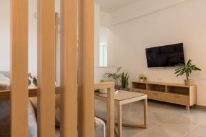 a living room with a table and a tv on a wall at Eden of grameno Luxury sea view apartment in Palaiochóra