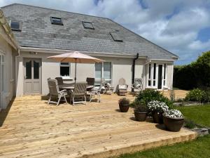a wooden deck with a table and chairs and an umbrella at Links Close, Rosslare Strand, Ireland in Rosslare