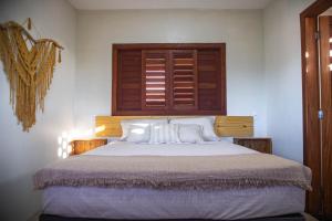 a bedroom with a large bed with a wooden headboard at Zero Meia Um Pousada in São Miguel do Gostoso