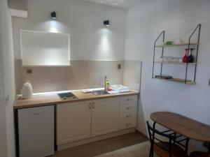 a kitchen with white cabinets and a sink and a table at Apartment Karmen in Sumartin