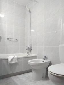 a white bathroom with a toilet and a bath tub at Hotel Capital de Galicia in Santiago de Compostela