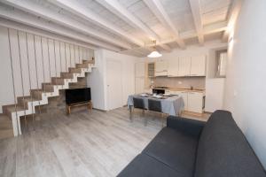 ein Wohnzimmer mit einem Sofa, einem Tisch und einer Treppe in der Unterkunft Appartamento Al Campanile in Montinelle