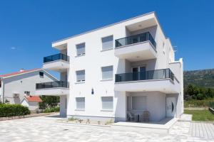 a white building with balconies and a blue sky at Delminium in Kaštela