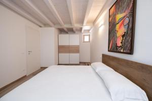 ein Schlafzimmer mit einem weißen Bett und einem Gemälde an der Wand in der Unterkunft Appartamento Al Campanile in Montinelle