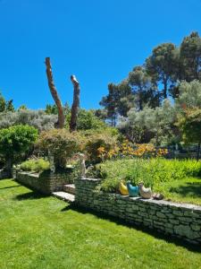 un jardín con una pared de piedra y algunas plantas en Le Mas des Anges, en Cheval Blanc