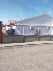 a white building with a fence next to a street at Casa Carmen in Bargas
