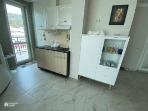 uma cozinha com armários brancos e piso em azulejo em Amore Beach элитный готельный комплекс em Elenite