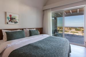 ein Schlafzimmer mit einem Bett und einem großen Fenster in der Unterkunft ALERÓ Seaside Skyros Resort in Skyros