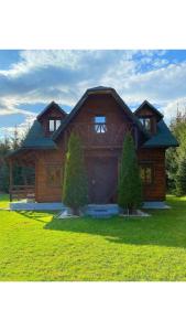 une grande maison en bois avec deux arbres devant elle dans l'établissement Domek drewniany z kominkiem, à Tomczyn