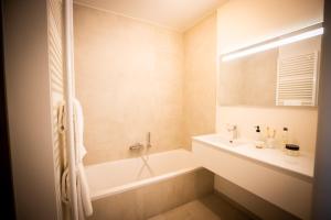 a white bathroom with a tub and a sink at La Risacca, Luxurious, 3 bedroom, sea view design apartment in Cadzand