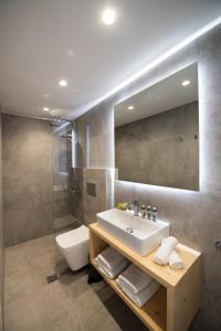 a bathroom with a sink and a toilet and a mirror at Azul Apartments in Nydri