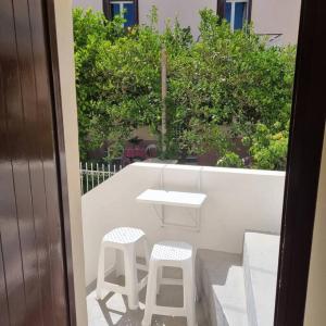 a table and two stools on a balcony with trees at Evi's touch 1 in Poros