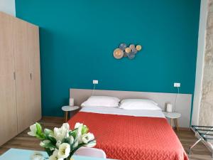 1 dormitorio con cama roja y pared azul en Bella Giulia, en Ragusa