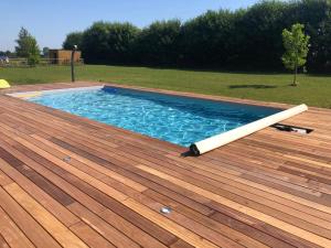 uma piscina num deque de madeira com um tubo branco em Logement neuf avec jardin privé 4 couchages Option piscine em Les Iffs