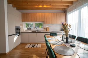 a kitchen with a wooden table with green chairs and a kitchen with white cabinets at Chata Lesnička in Nová Lesná