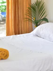 uma cama branca com uma almofada e uma planta em Guesthouse Congo Tempisque em Libéria