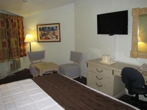 Habitación de hotel con cama, escritorio y TV. en A-1 Budget Motel, en Homestead