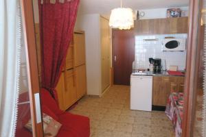 a kitchen with a red curtain and a red couch at Studio au calme face aux montagnes dans station de ski in La Morte