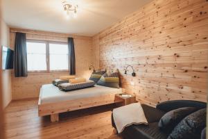 a bedroom with a wooden wall with a bed and a couch at Hiasl Zirbenhütte in Hochrindl