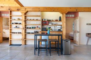 una cocina con mesa, taburetes y estanterías en Earthship retreat + 2 spas + incredible views., en Santa Fe