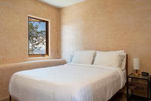 a bedroom with a white bed and a window at Earthship retreat + 2 spas + incredible views. in Santa Fe
