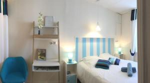 een kleine slaapkamer met een bed en een blauwe stoel bij Logis des Lauriers Roses in Marennes