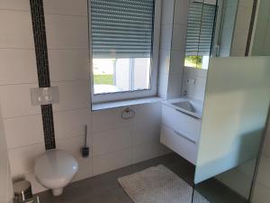 un bagno con un water, un lavandino e una finestra di ***FeWo Am Achterwasser *** a Lütow Altre 16 foto