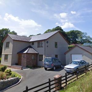 a house with two cars parked in a driveway at Criccieth Family holiday house in Morfa Bychan