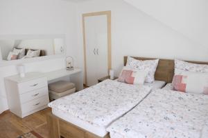 a white bedroom with a bed and a desk at Apartman Sveti Rok in Požega
