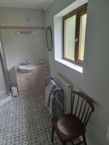 ein Badezimmer mit einem Waschbecken, einem Stuhl und einem Spiegel in der Unterkunft Criccieth Family holiday house in Tremadoc