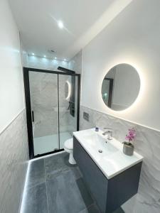 a bathroom with a sink and a toilet and a mirror at Coastline Retreats - Stunning Balcony Apartment with Sea Views - Alice in Wonderland Themed Secret Room - Luxury Copper Bath in Master Bedroom in Southbourne