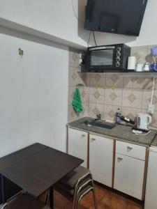 uma pequena cozinha com um lavatório e uma mesa em Complejo las Palmeras em Godoy Cruz