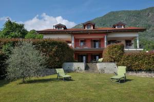 una casa con sillas verdes en el patio en Villetta dei Pascoli, en Baveno