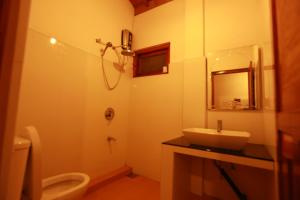 Un baño con lavabo, inodoro y espejo. en Tea Garden Holiday Inn, en Ella