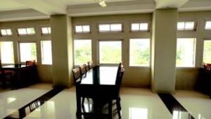 a room with a table and chairs and windows at KTDC Garden House in Palakkad