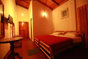 Una habitación con dos camas y una mesa dentro. en Tea Garden Holiday Inn, en Ella