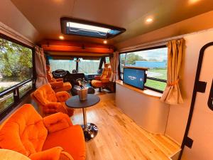 a living room with orange chairs and a tv in an rv at Vintage 1980s Winnebago in Oxford